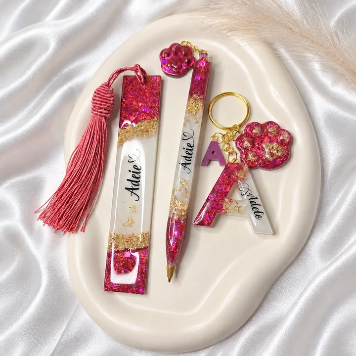 Conjunto de caneta, marcador de páginas e chaveiro em resina rosa, branca e dourada